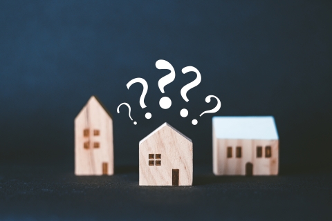 Three small wood houses with question marks.