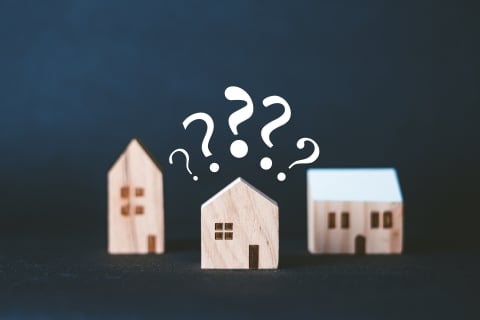 Three small wood houses with question marks.