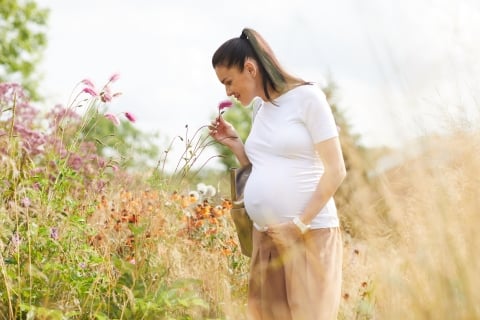 Woman smelling a flower in a field.